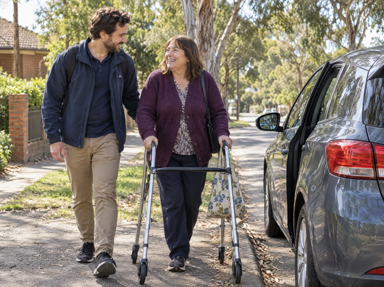 Support worker walking beside a woman using a walking frame towards a car